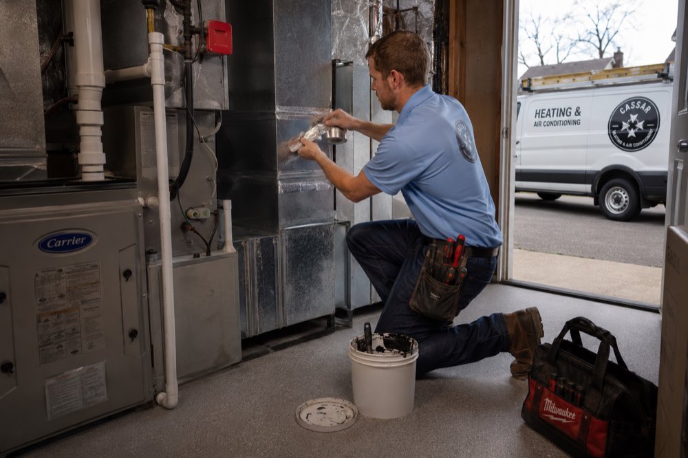Cassar HVAC technician sealing ductwork joints with foil tape in Oshawa, Ontario
